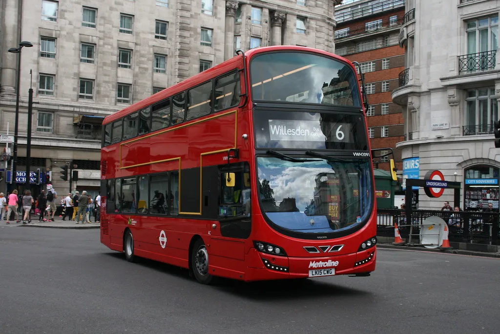 A red double-decker bus showing route 6 to Willesden, turning at Marble Arch beside the Underground station entrance