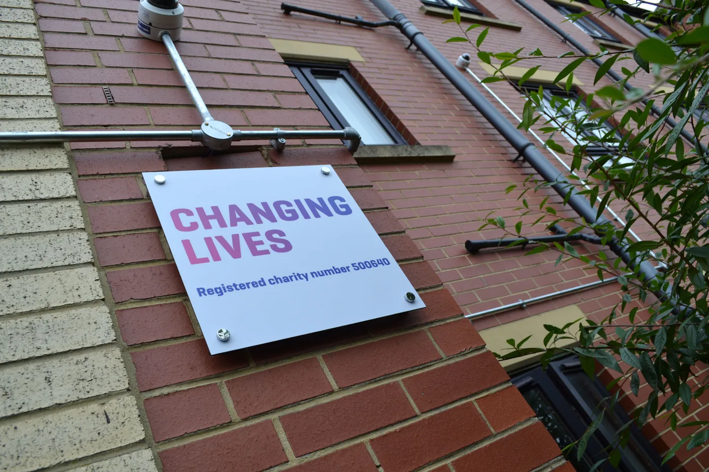 The Changing Lives sign on the wall of a brick building