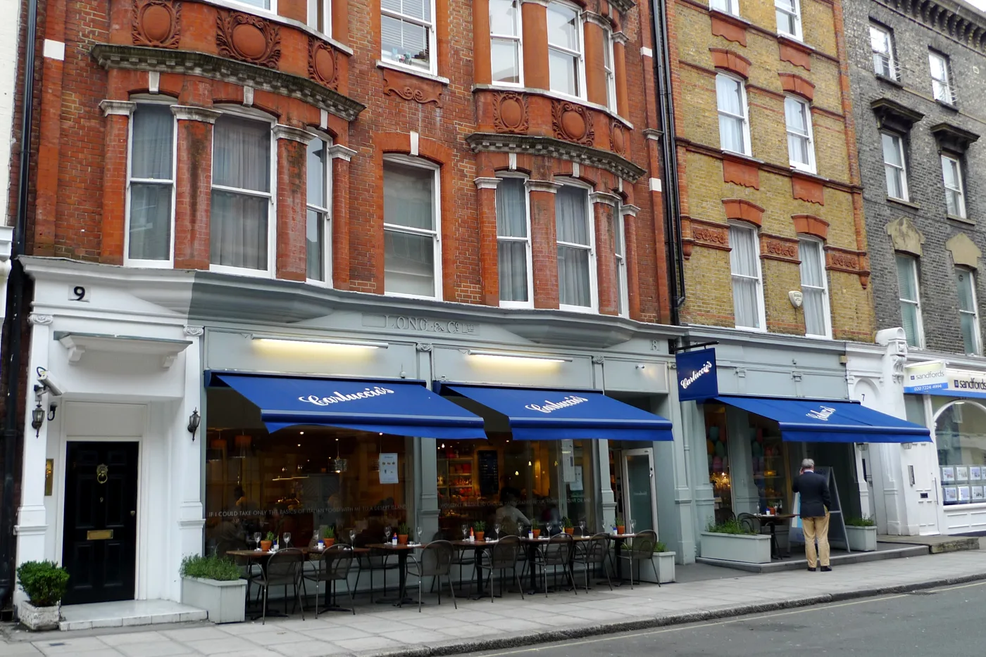 Tables and chairs on the pavement under shop awnings in Marylebone, W1